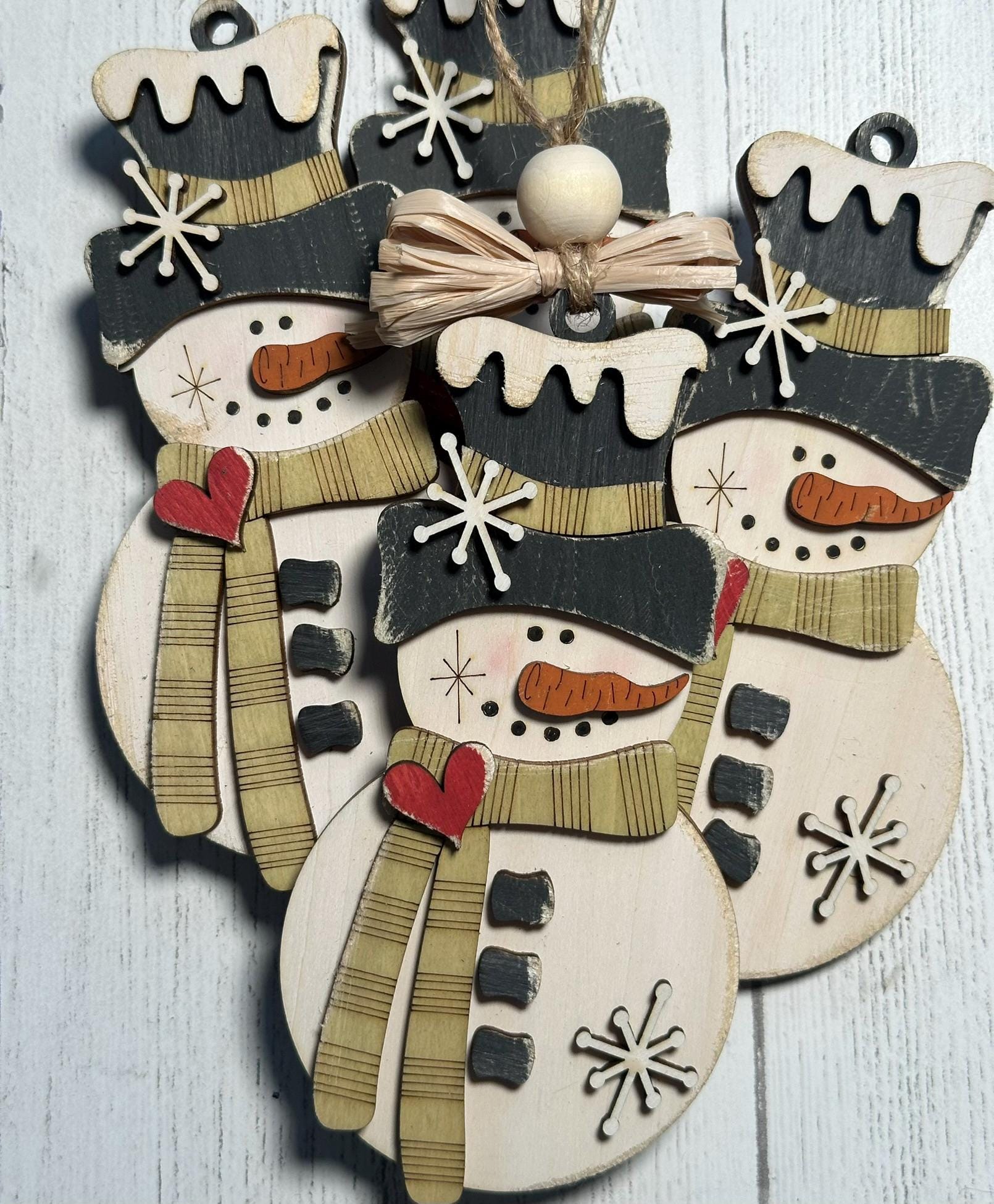 4 rustic snowman ornaments with light green scarf and raffia bow