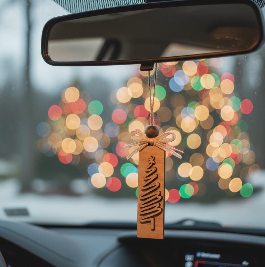Rustic wood Christmas tree ornament hanging from car mirror with festive bokeh lights.