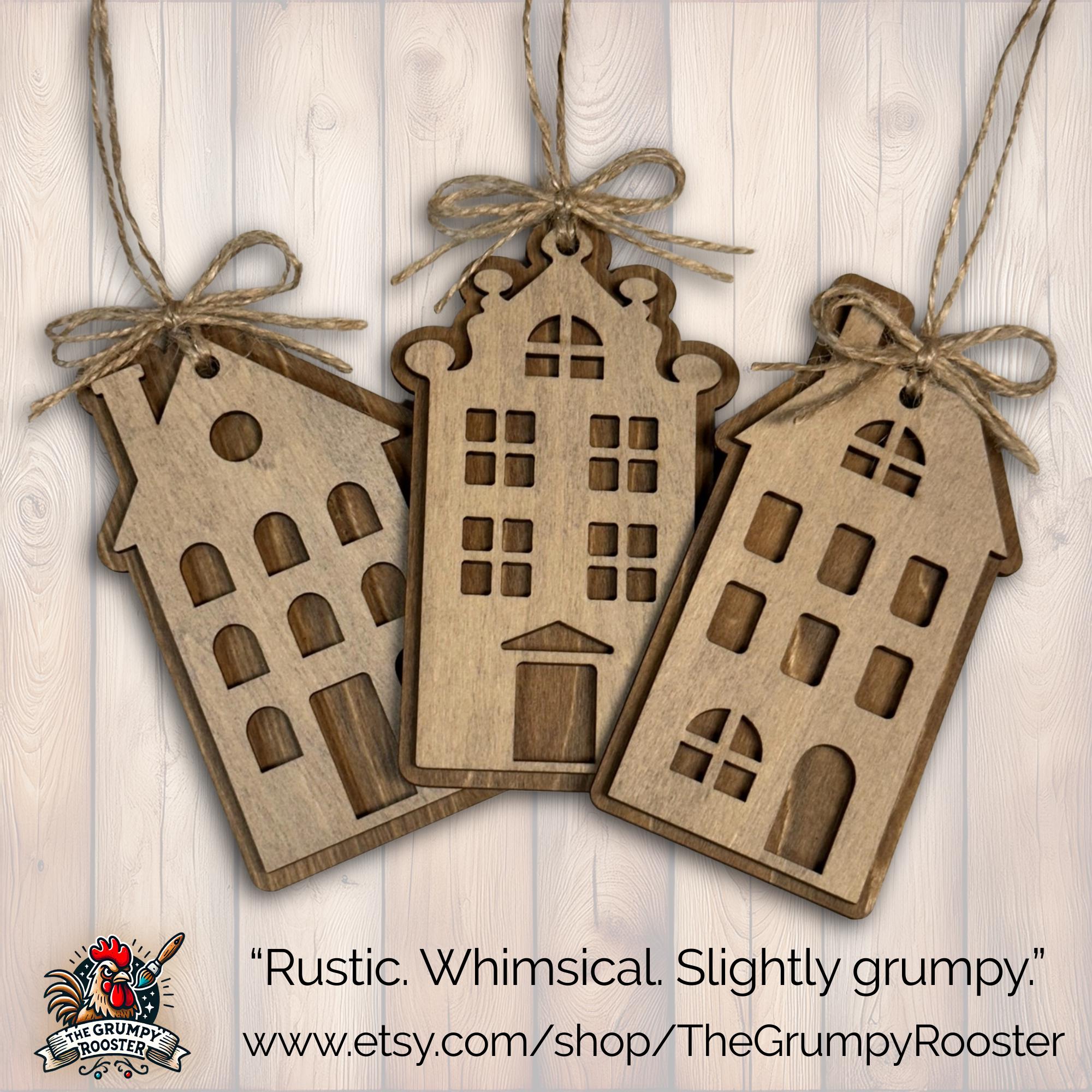 Rustic wooden house ornaments hanging on Christmas tree with warm lights and cozy farmhouse decor.