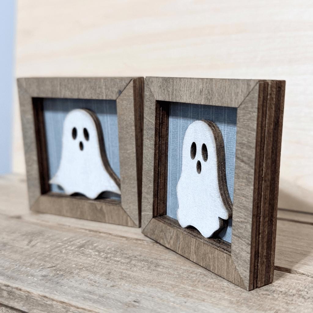 two wooden frames with ghost-like silhouettes displayed inside them.