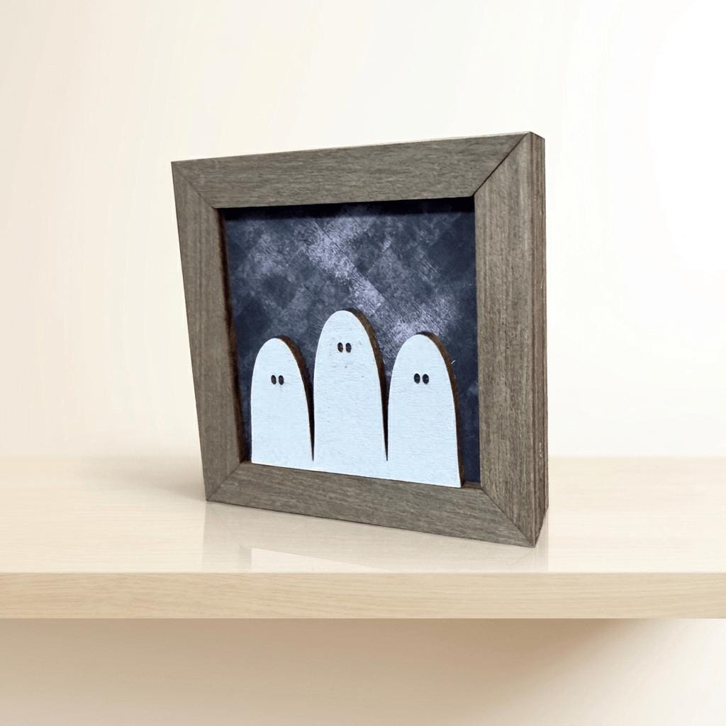 A wooden picture frame containing a black and white image of three ghostly figures.