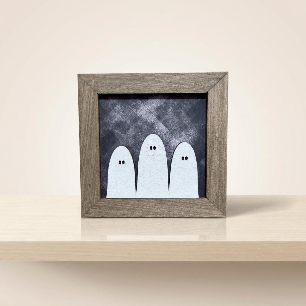 A wooden frame containing a black and white image of three ghostly figures.